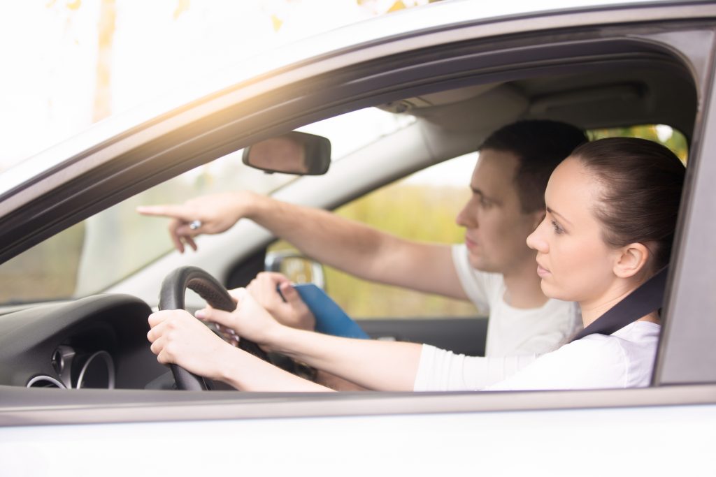 young woman driving man pointing direction
